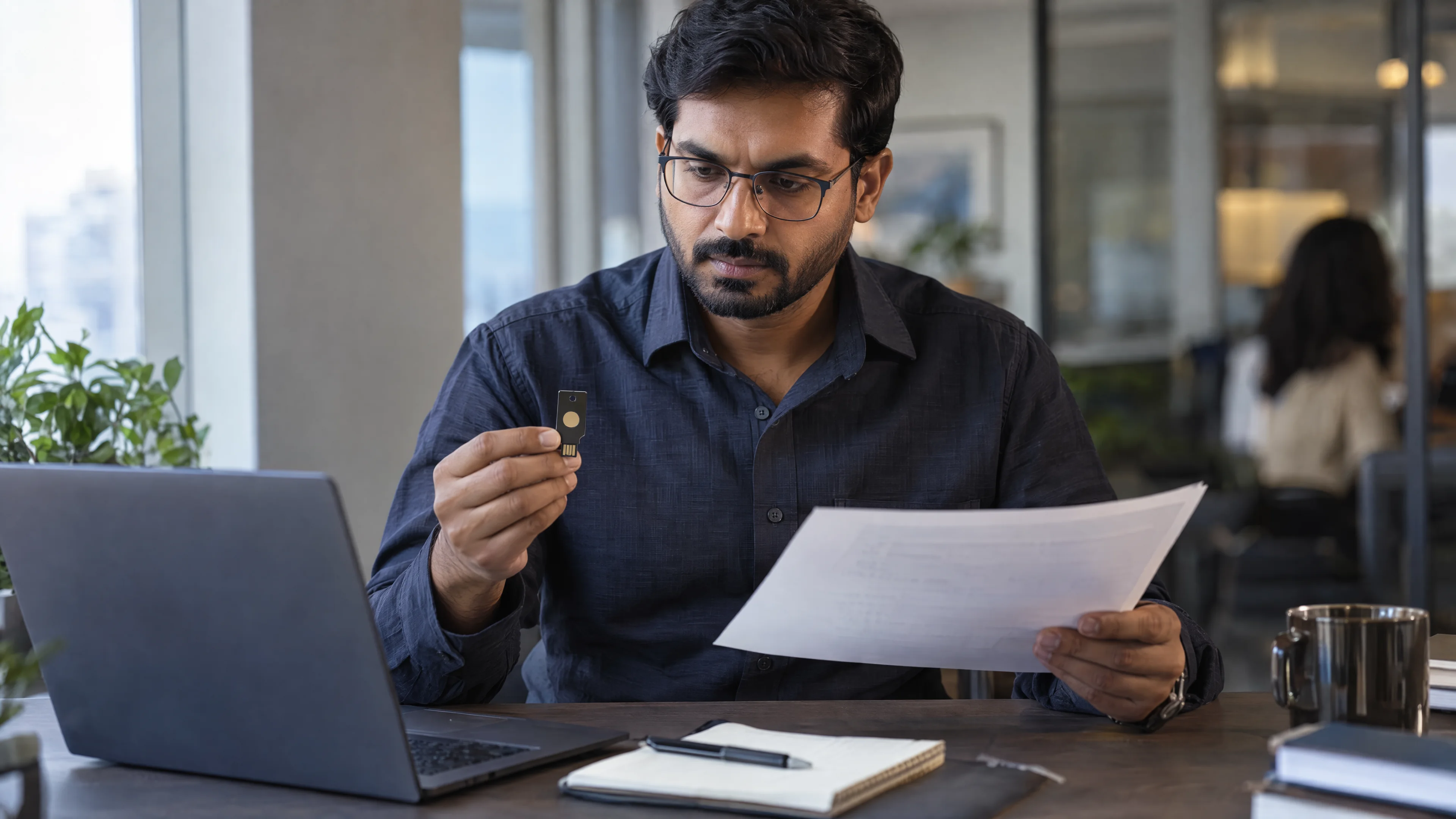 Access reviewer checking a visitor record beside a hardware security key.
